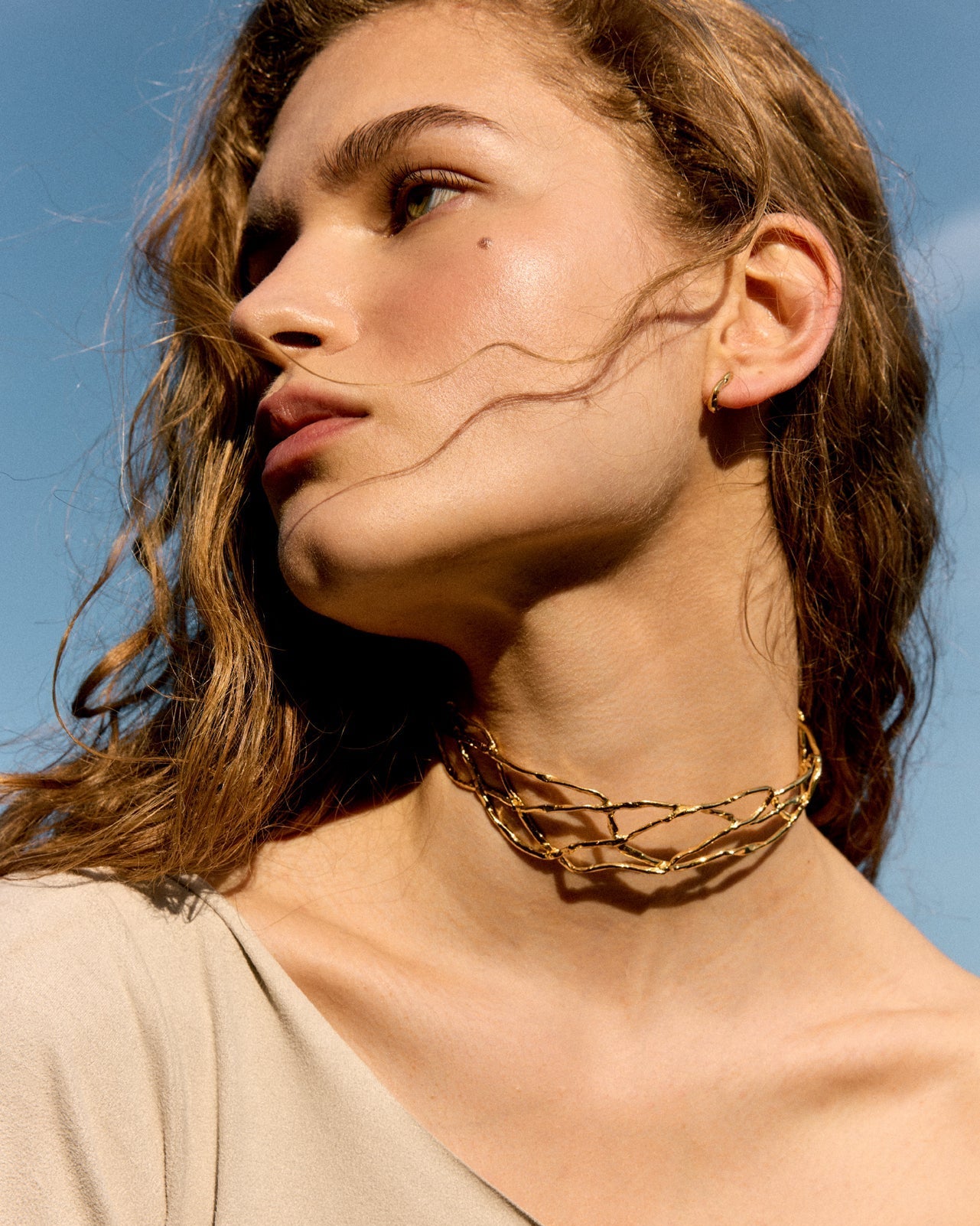 Medium shot of a model in a linen dress accessorized with contemporary design earrings from the Halos capsule collection.
